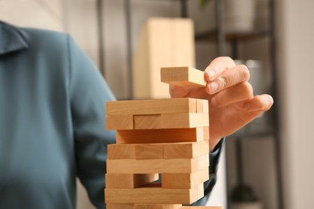 Woman building tower with wooden blocks indoors, closeupの写真素材
