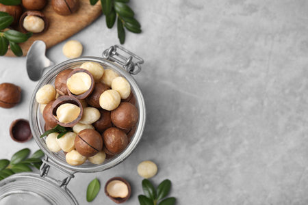 Tasty Macadamia nuts in jar on light gray table, flat lay. Space for textの写真素材