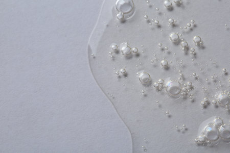 Clear cosmetic serum on white background, macro view. Space for text
