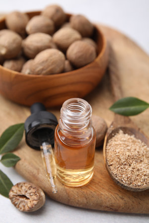 Nutmeg essential oil, nuts and leaves on light tableの写真素材