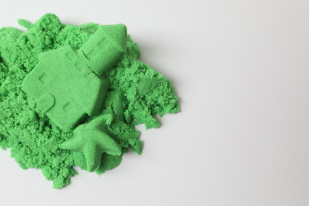 Castle and starfish made of green kinetic sand isolated on white, top view