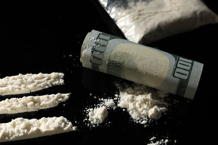 Drug addiction. Cocaine and rolled dollar banknote on black table, closeupの写真素材