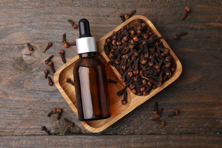 Clove oil in bottle and dried buds on wooden table, top viewの写真素材