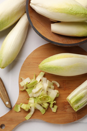 Fresh raw Belgian endives (chicory) on white tiled table, flat lay