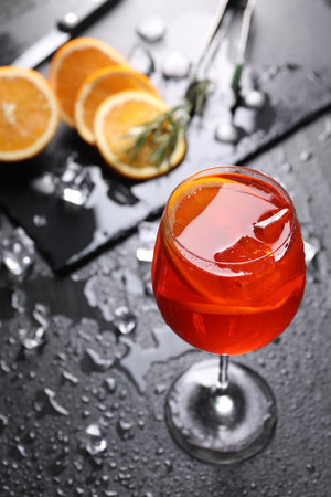 Glass of tasty spritz cocktail with orange slices and ice cubes on dark gray table, above viewの写真素材
