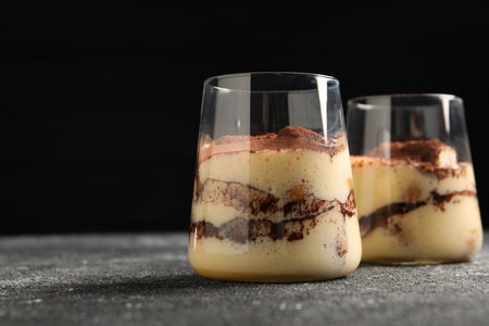 Delicious tiramisu in glasses on gray textured table, closeup. Space for textの写真素材