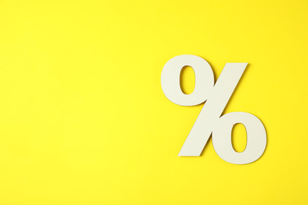 White percent sign on yellow background, top view. Space for textの写真素材