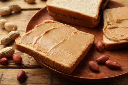 Tasty peanut butter sandwiches and peanuts on wooden table, closeupの写真素材