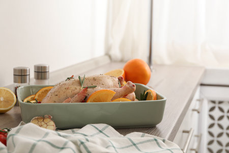 Chicken with orange slices in baking pan on wooden countertopの写真素材