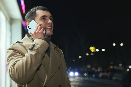 Man talking by smartphone on night city street, space for textの写真素材