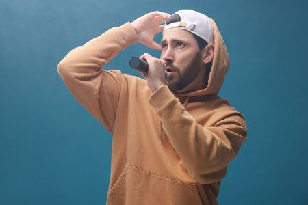 Singer with microphone rapping on light blue backgroundの写真素材
