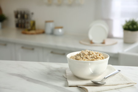 Breakfast time. Tasty oatmeal in bowl on white marble table. Space for textの写真素材