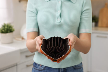 Woman with empty wallet at home, closeup