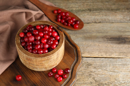 Cranberries in bowl and spoon on wooden table, space for textの写真素材