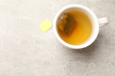 Brewing tea. Cup with tea bag on light table, top view. Space for textの写真素材