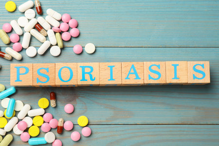 Word Psoriasis made of cubes with letters and pills on light blue wooden table, flat layの写真素材