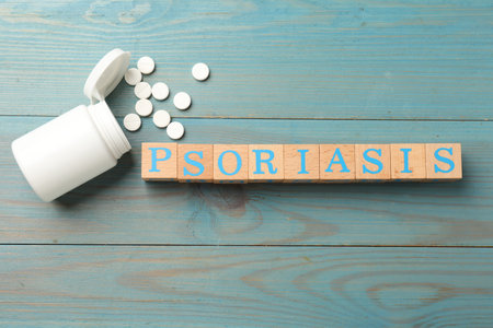 Word Psoriasis made of cubes with letters and pills on light blue wooden table, flat layの写真素材