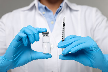 Doctor holding syringe and glass vial, closeup viewの写真素材