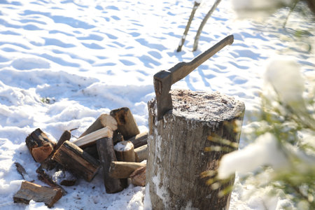 Metal ax in wooden log outdoors on sunny winter dayの写真素材