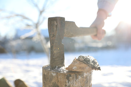Man taking ax out of wooden log outdoors on sunny day, closeupの写真素材