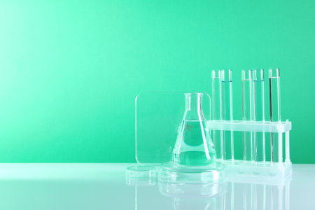 Laboratory analysis. Different glassware on table against green background, space for textの写真素材