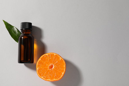 Aromatic tangerine essential oil in bottle, leaf and citrus fruit on gray table, top view. Space for textの写真素材