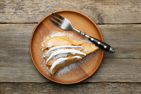 Piece of tasty homemade quince pie with powdered sugar and fork on wooden table, top viewの写真素材