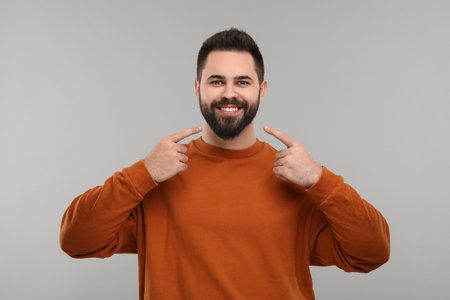 Man showing his clean teeth and smiling on gray backgroundの写真素材