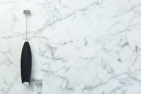 Black milk frother wand on white marble table, top view. Space for textの写真素材