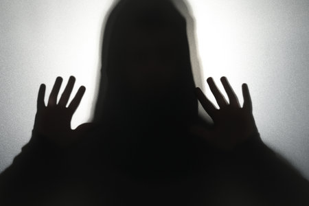 Silhouette of ghost behind glass against gray background