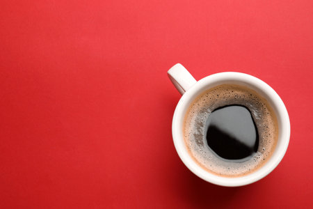 Fresh coffee in cup on red background, top view. Space for textの写真素材