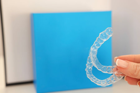 Woman with transparent dental aligners on blurred background, closeup. Space for textの写真素材