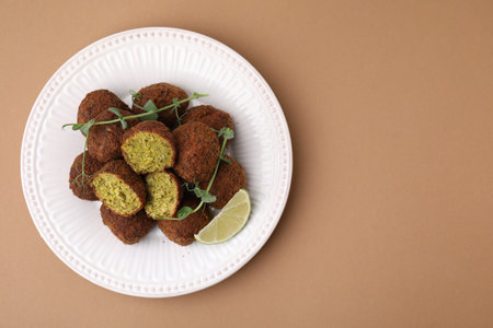 Delicious falafel balls, lime slice and microgreens on pale brown background, top view. Space for textの写真素材