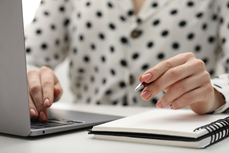 E-learning. Woman taking notes during online lesson at table indoors, closeupの写真素材