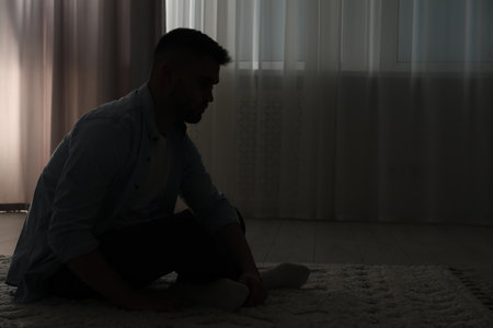 Silhouette of sad man in dark room. Space for textの写真素材