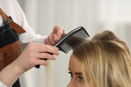 Hair styling. Professional hairdresser combing woman's hair in salon, closeupの写真素材