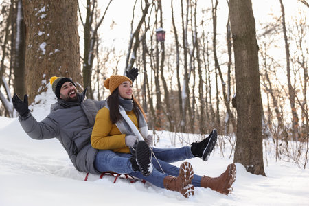 Happy young couple sledding outdoors on winter dayの写真素材