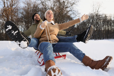 Happy young couple sledding outdoors on winter dayの写真素材
