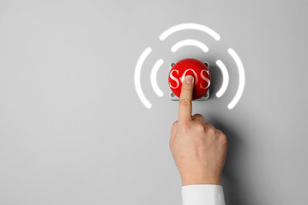 Man pressing red SOS button at white background, closeup