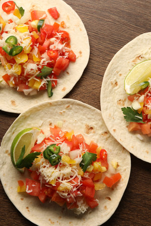 Delicious tacos with vegetables and lime on wooden table, top viewの写真素材