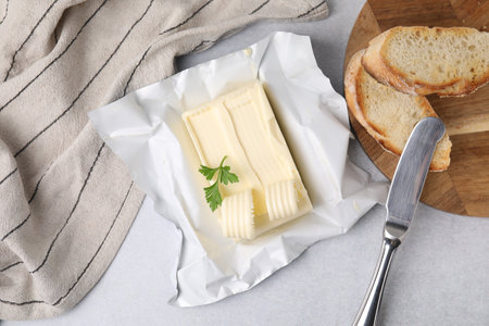Tasty butter with curls, slices of bread and knife on light gray table, flat layの写真素材