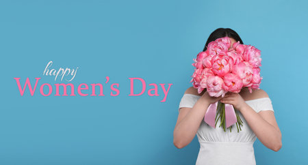 Happy Women's Day, Charming lady holding bouquet of beautiful flowers on light blue backgroundの写真素材