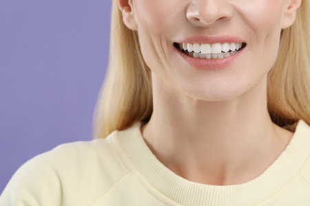 Woman with clean teeth smiling on violet background, closeupの写真素材