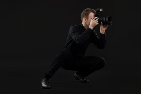 Professional photographer taking picture on black backgroundの写真素材