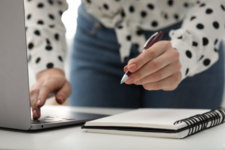 E-learning. Woman taking notes during online lesson at table indoors, closeupの写真素材