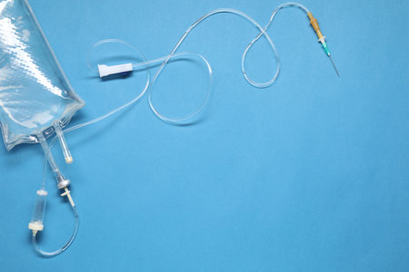 IV infusion set on light blue background, top view. Space for text
