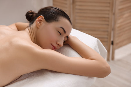 Beautiful woman relaxing on massage couch in spa salon, space for textの写真素材
