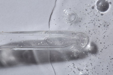 Pipette with cosmetic serum on white background, macro view