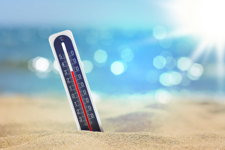 Thermometer on beach showing high temperature during summer dayの写真素材