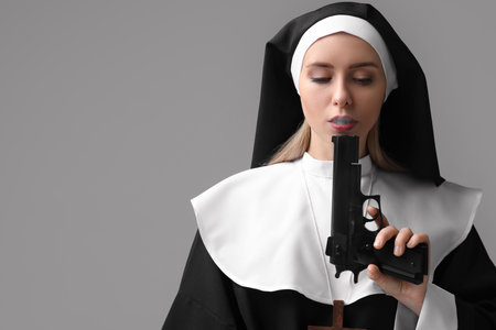 Woman in nun habit holding handgun on gray background. Space for textの写真素材